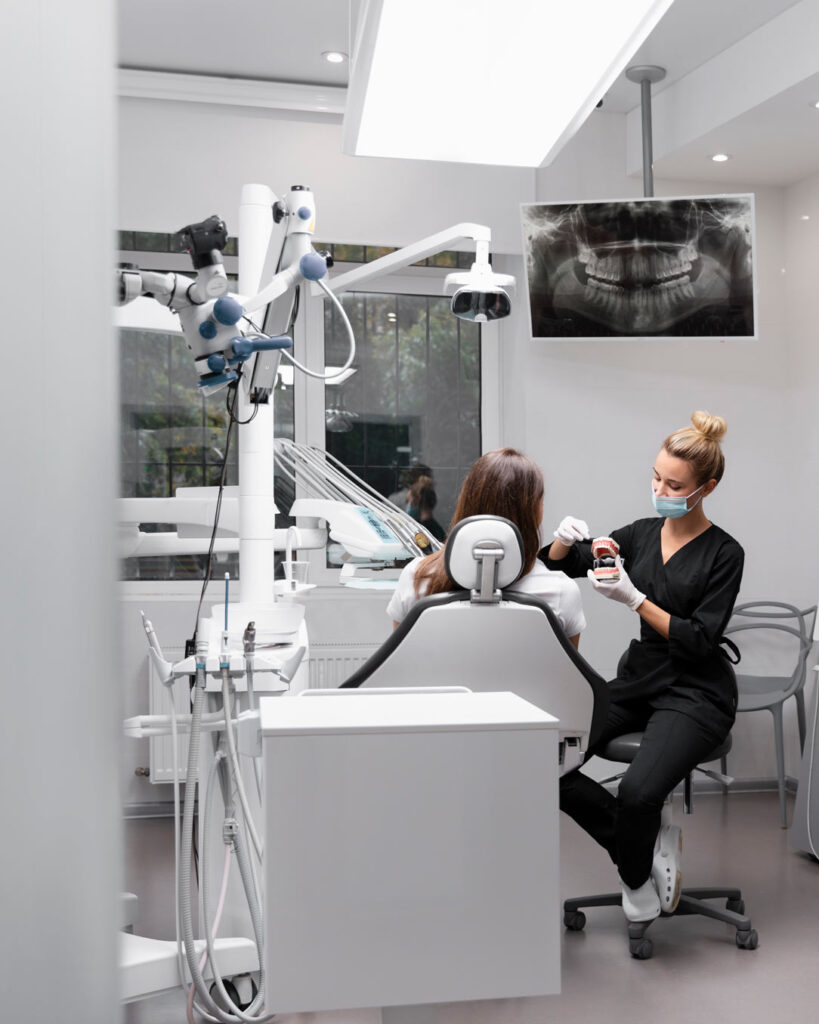 Vista de una sala de consulta de una clínica dental, se ve una dentista atendiendo a un paciente