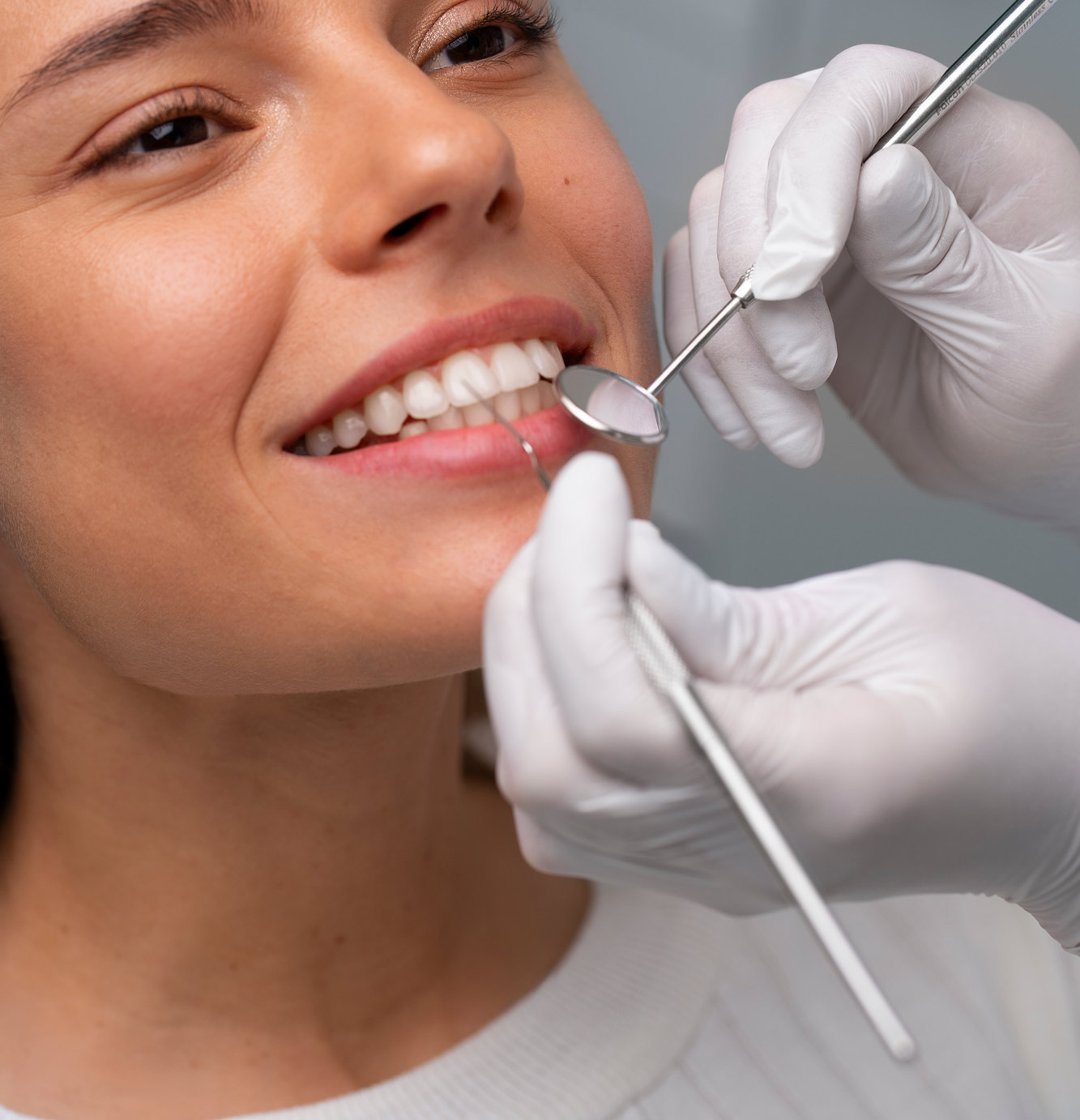 Boca de una chica siendo inspeccionada con instrumentos por las manos de una dentista