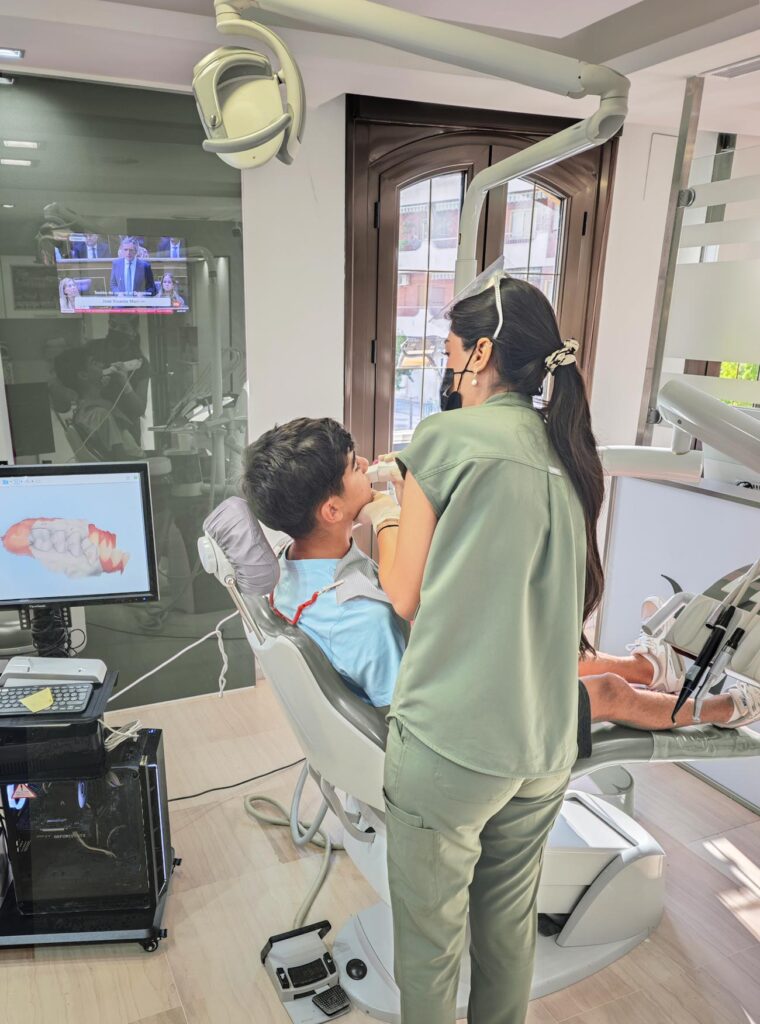 Dentista atendiendo a un paciente sentado en el sillón.