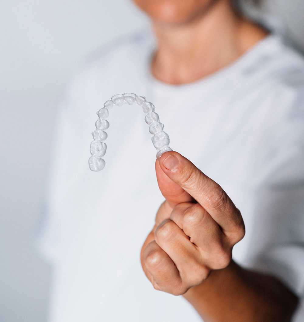 Persona mostrando en primer plano una funda Invisalign