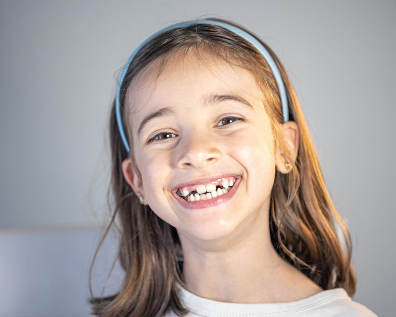 Niña sonriente mostrando sus dientes, algunos todavía de leche.
